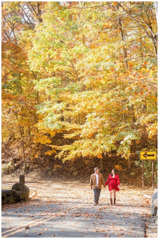 Couple walking along a path in a fall forest holding hands
