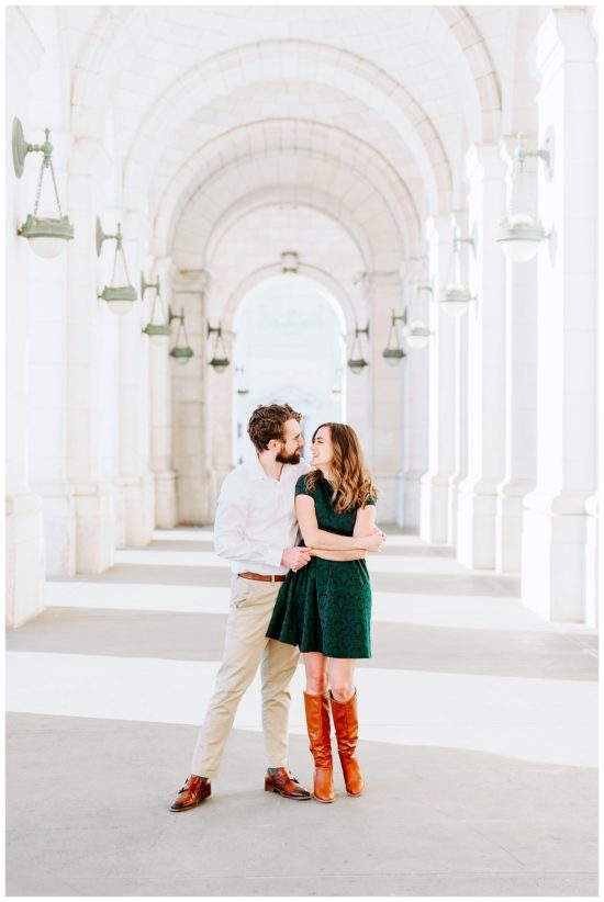 couple is hugging, standing under a white marble arch