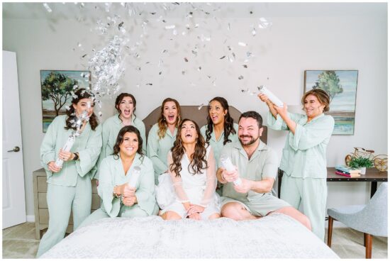 Bridal Party sits on couch popping confetti 
