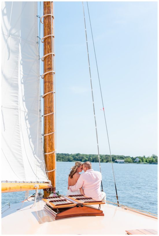 Bride and grooms sitting on the bow of a sailboat looking at the horizon