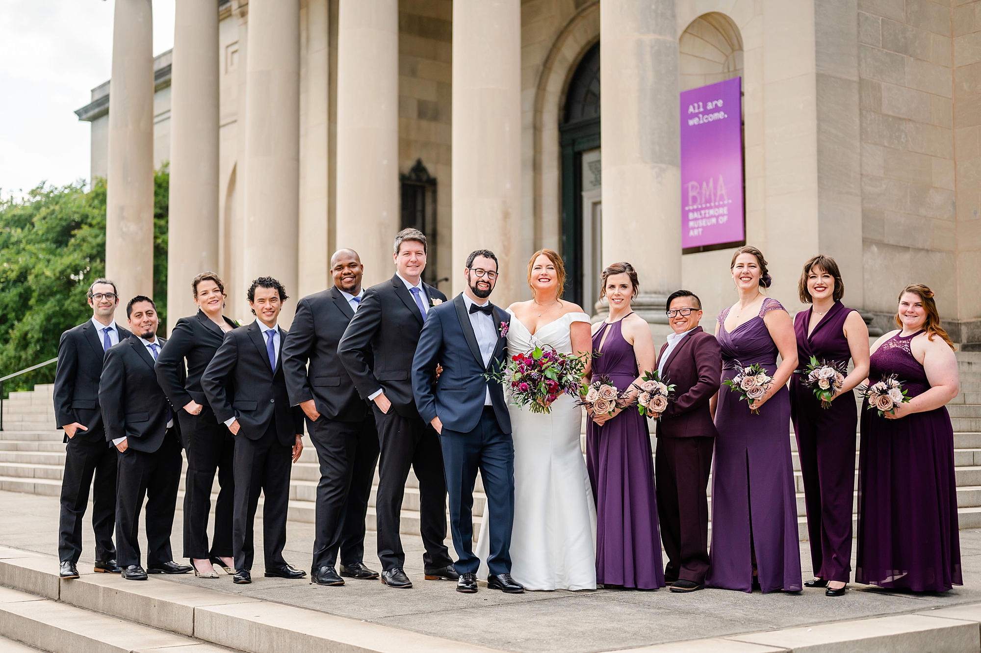 bride and groom pose with wedding party in plum and navy attire 