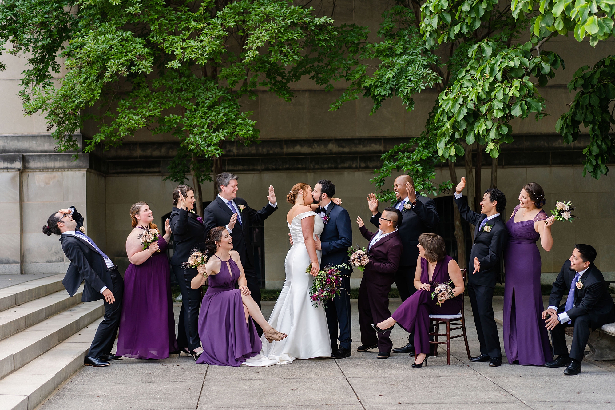 wedding party in navy and plum stand outside the Baltimore Museum of Art with bride and groom 