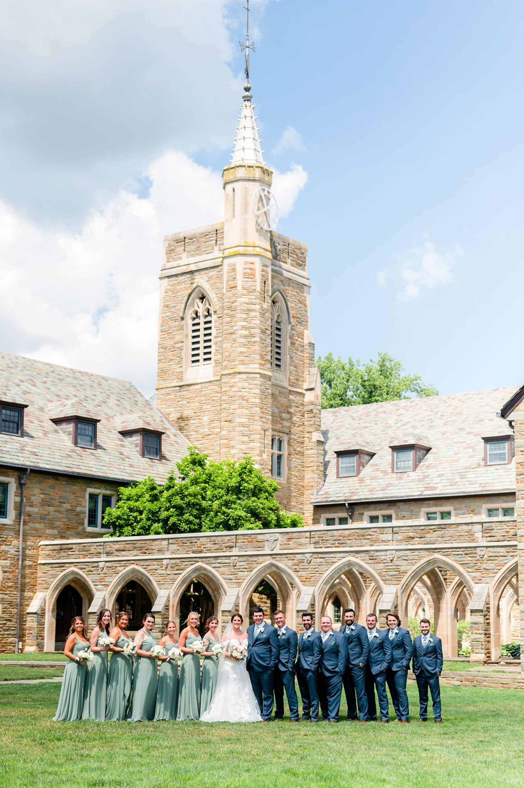 bride and groom pose with wedding party outside chapel at Saint Andrews School