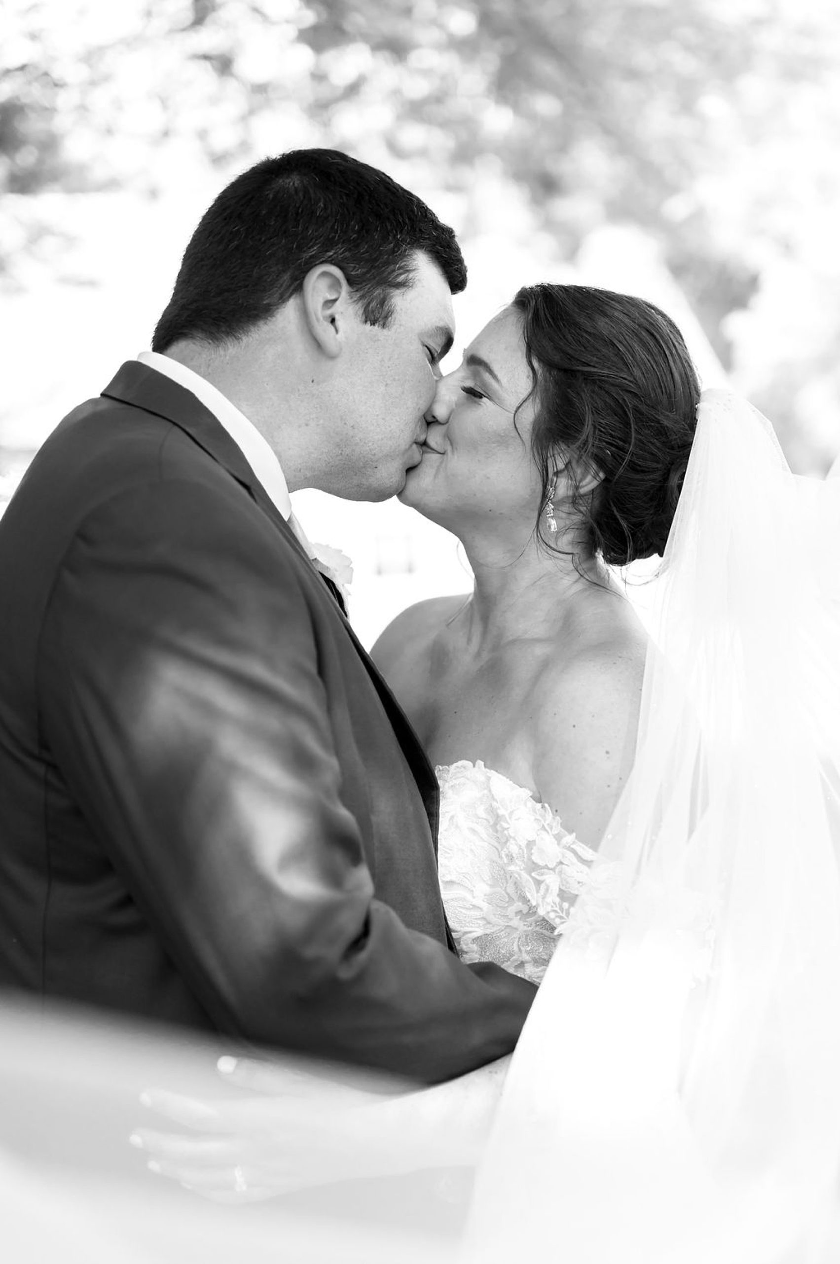 newlyweds kiss with bride's veil draped around them 