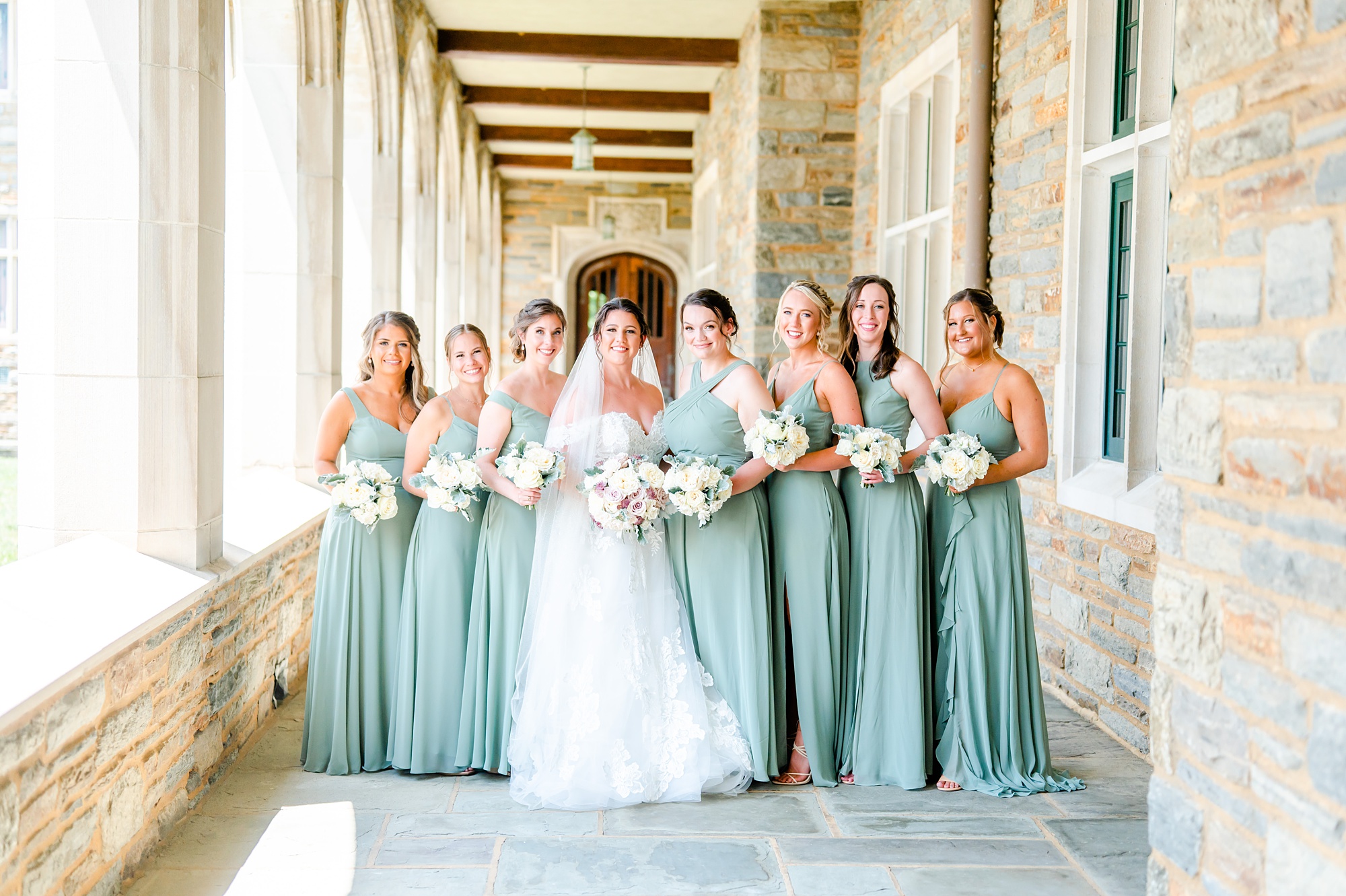 bride stands with bridesmaids in sage green gowns