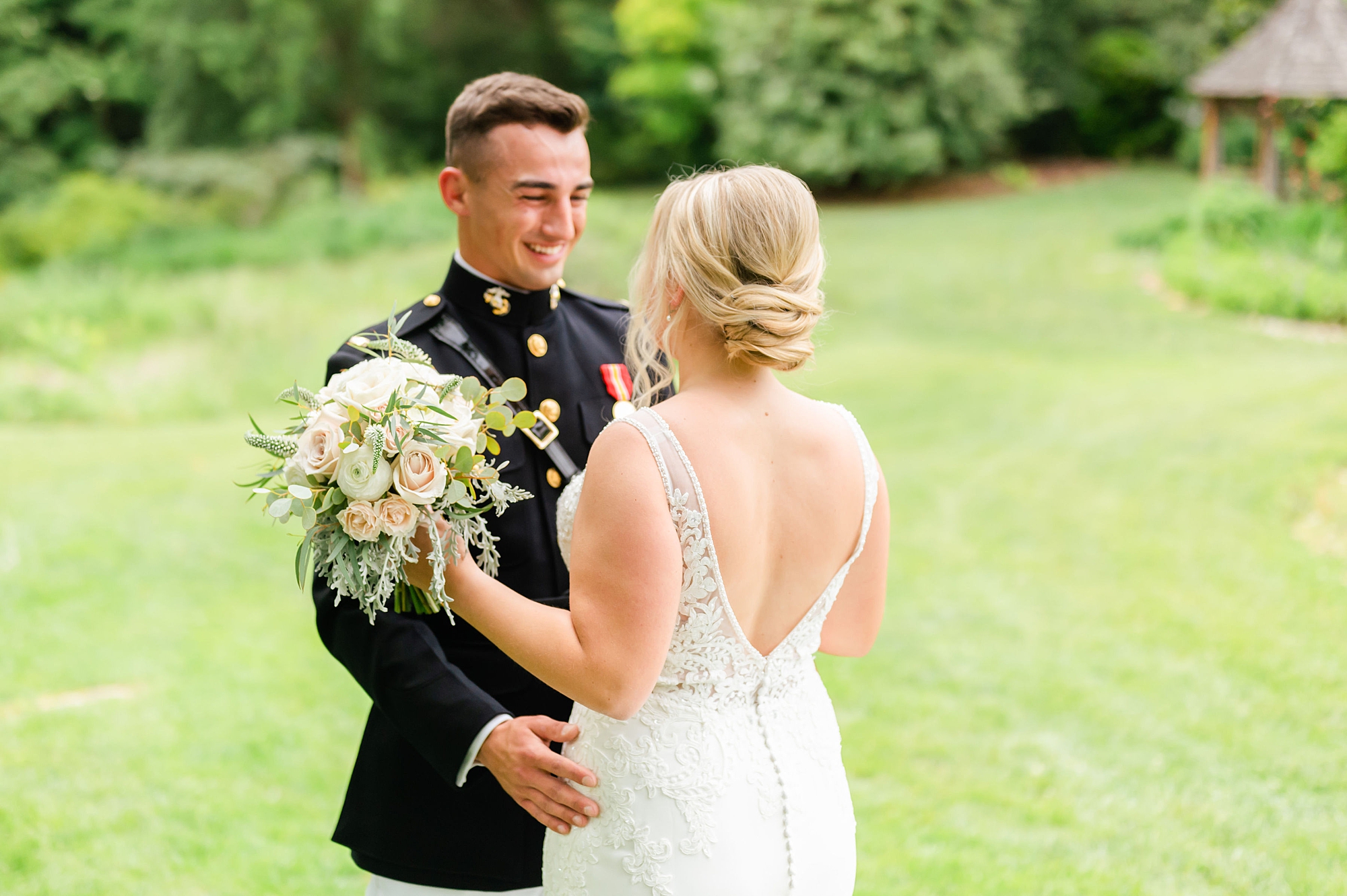 groom in Marine uniform smiles at bride during first look