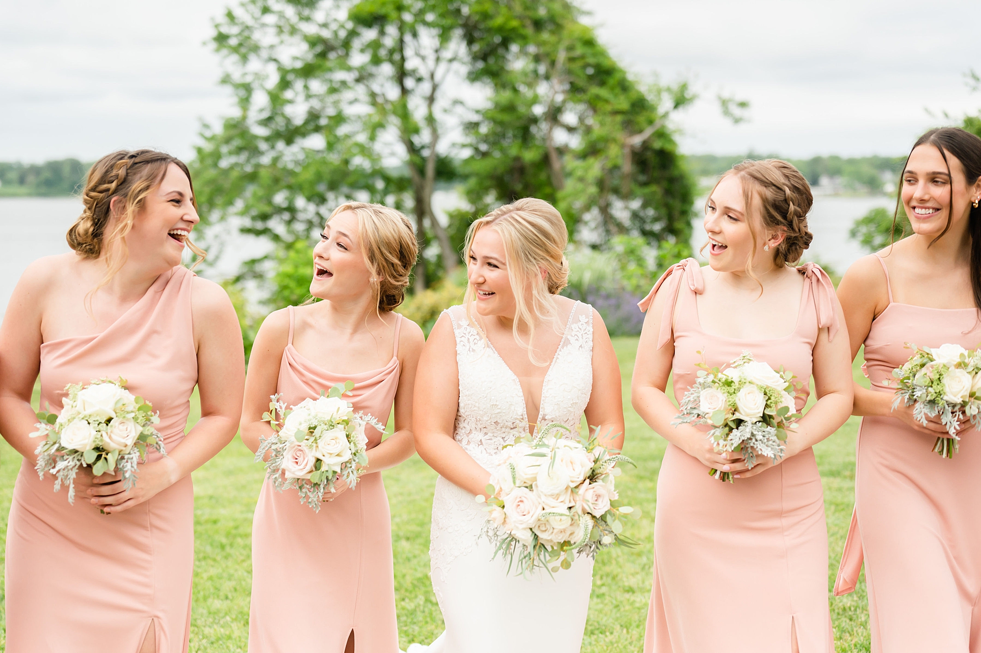 bride laughs with bridesmaids walking along water at Londontown Gardens