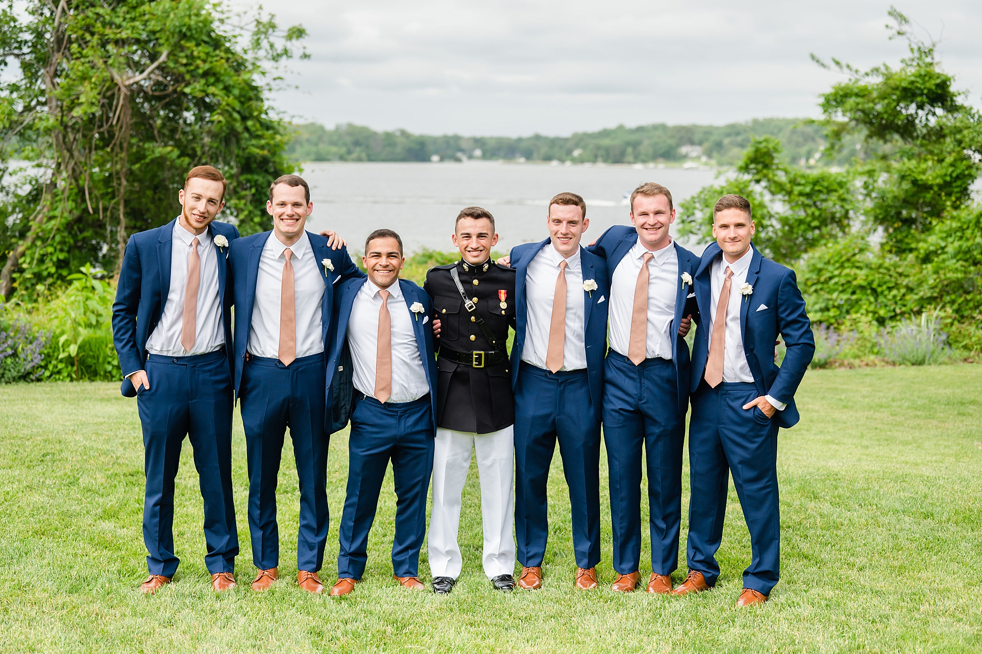 groom stands next to groomsmen in navy suits