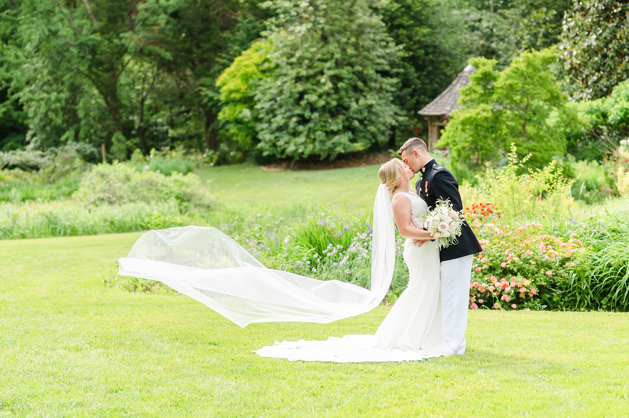 newlyweds kiss with bride's veil floating behind them in Londontown Gardens