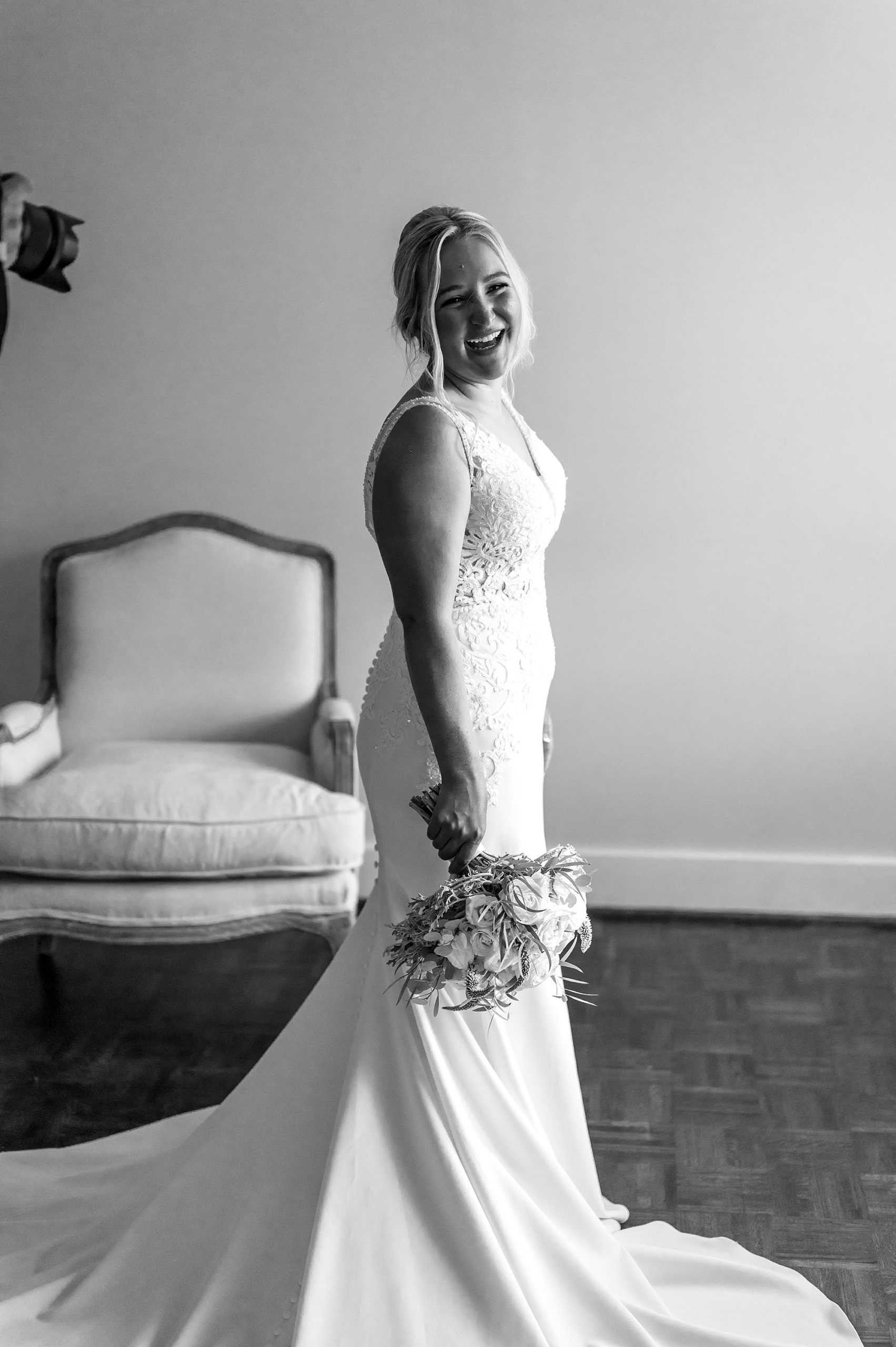 bride smiles holding bouquet by side in black and white portrait 