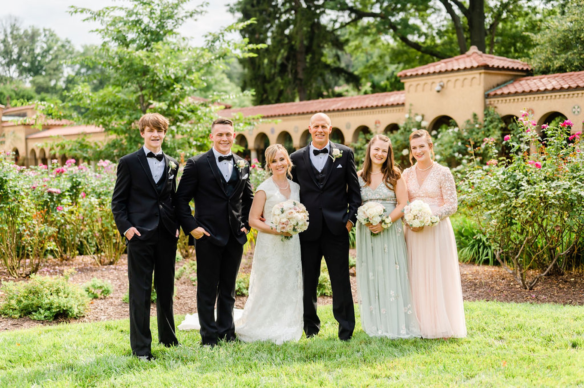 bride and groom pose with four kids in courtyard at Saint Francis Hall