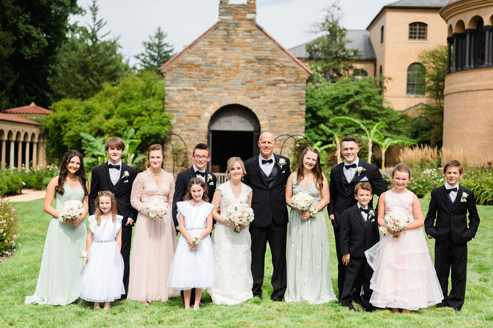 bride and groom pose with kids and wedding party in courtyard of Saint Francis Hall