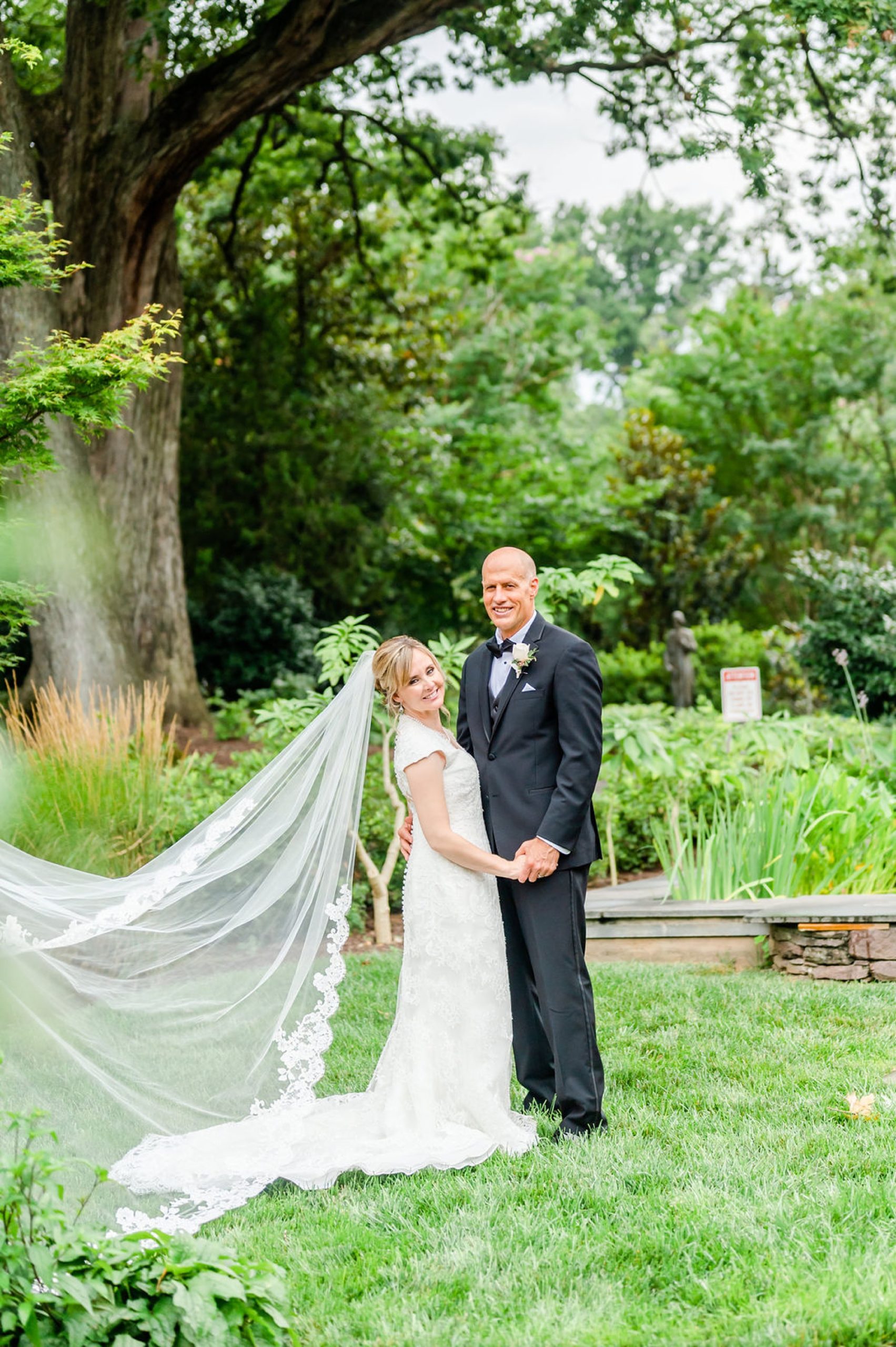 newlyweds hold hands in garden at Saint Francis Hall
