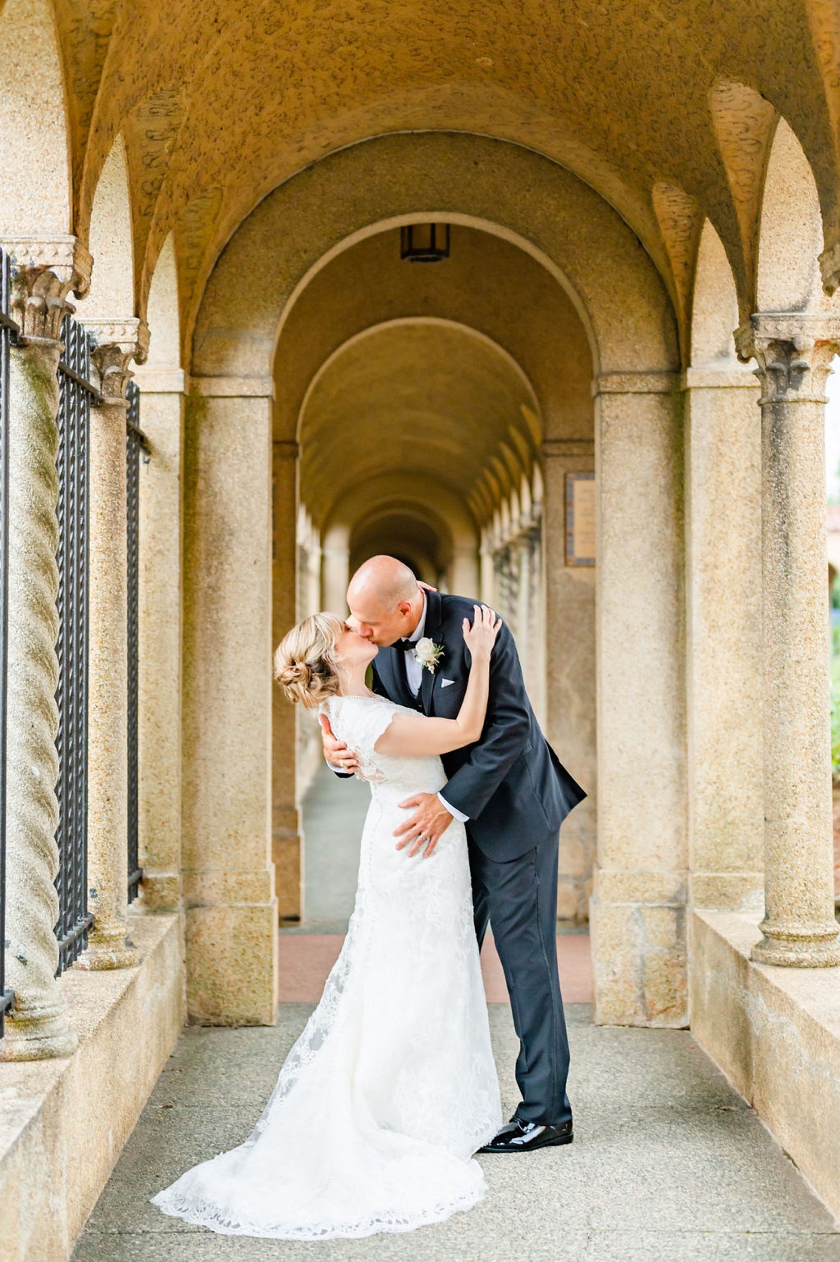 newlyweds kiss in stone archway at Saint Francis Hall