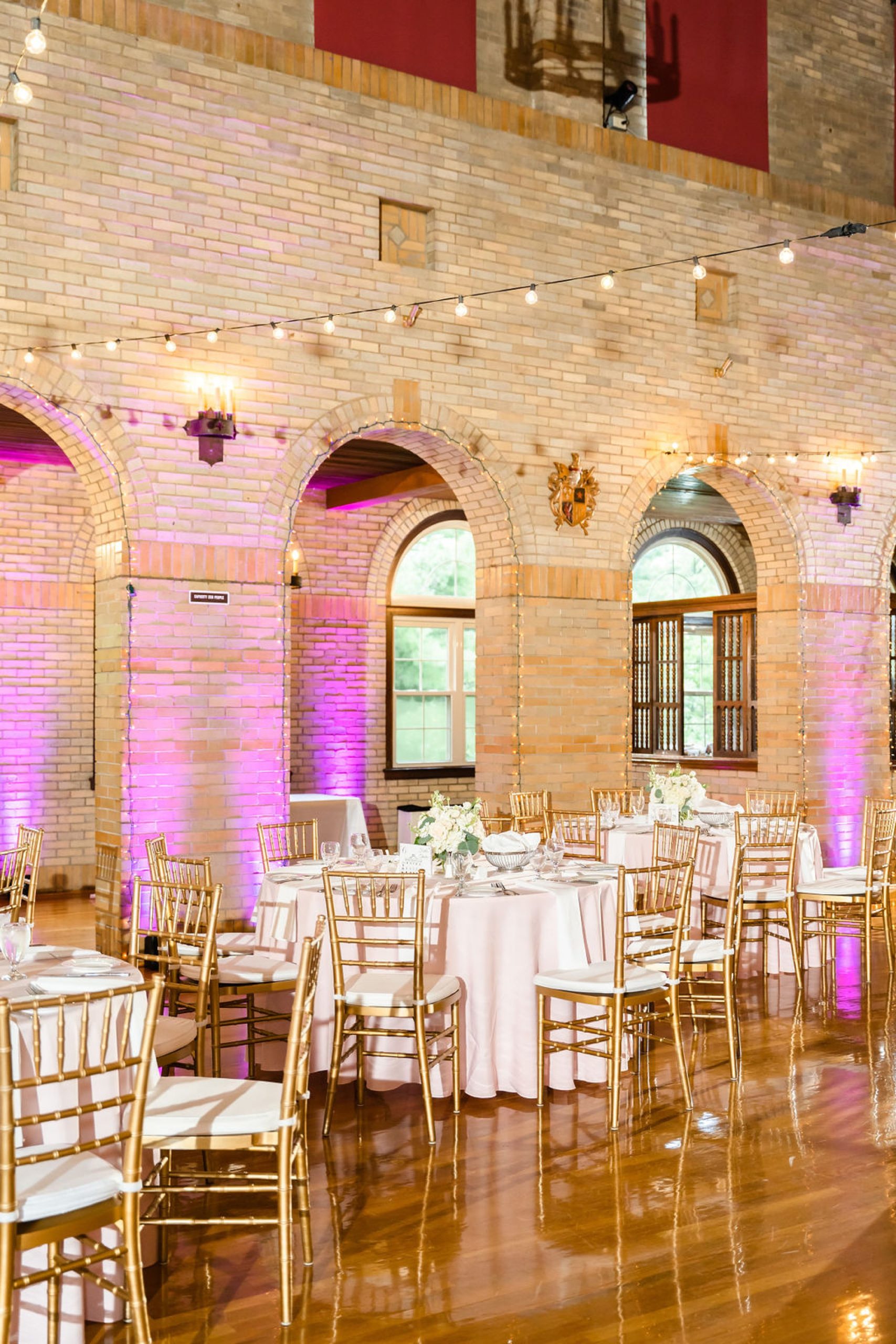 wedding reception inside Saint Francis Hall with bistro lights and gold details 