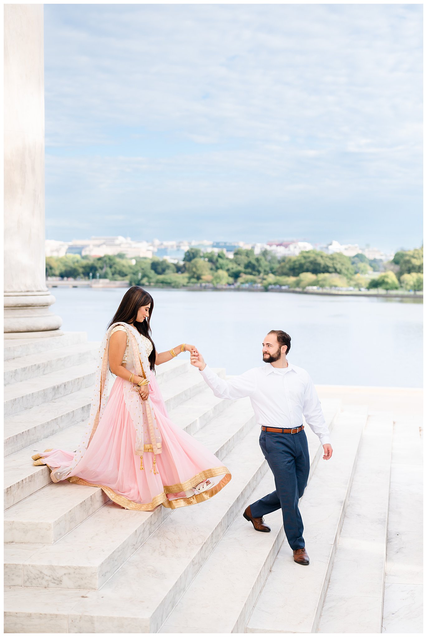 groom leads bride in pink sari dress down steps of Jefferson Memorial