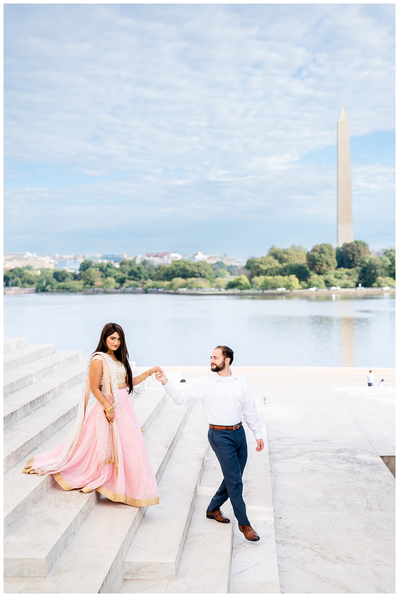 groom helps bride in pink sari down steps of Jefferson Memorial by Tidal Basin