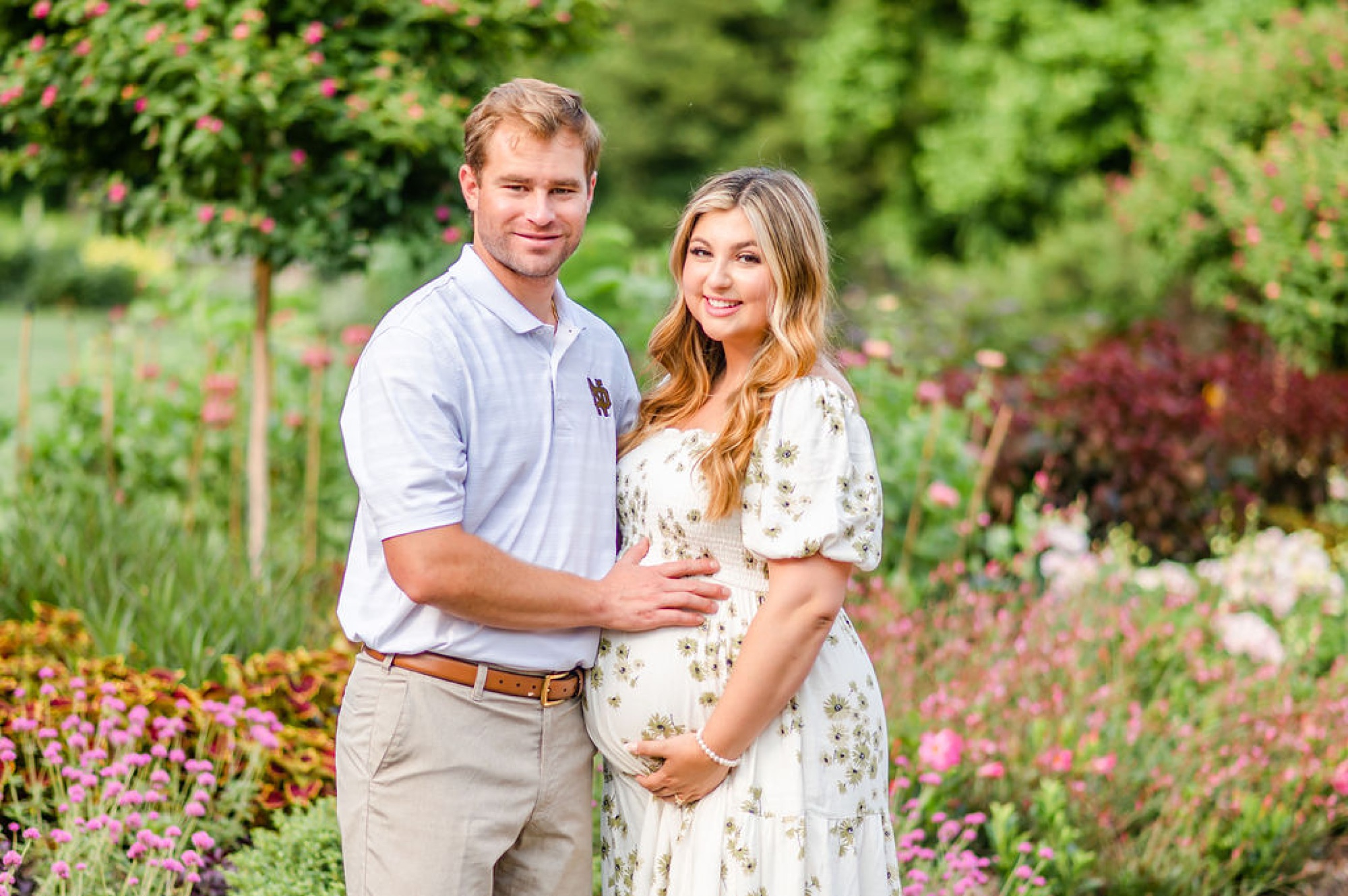 husband touches wife's pregnant belly during Longwood Gardens maternity portraits 