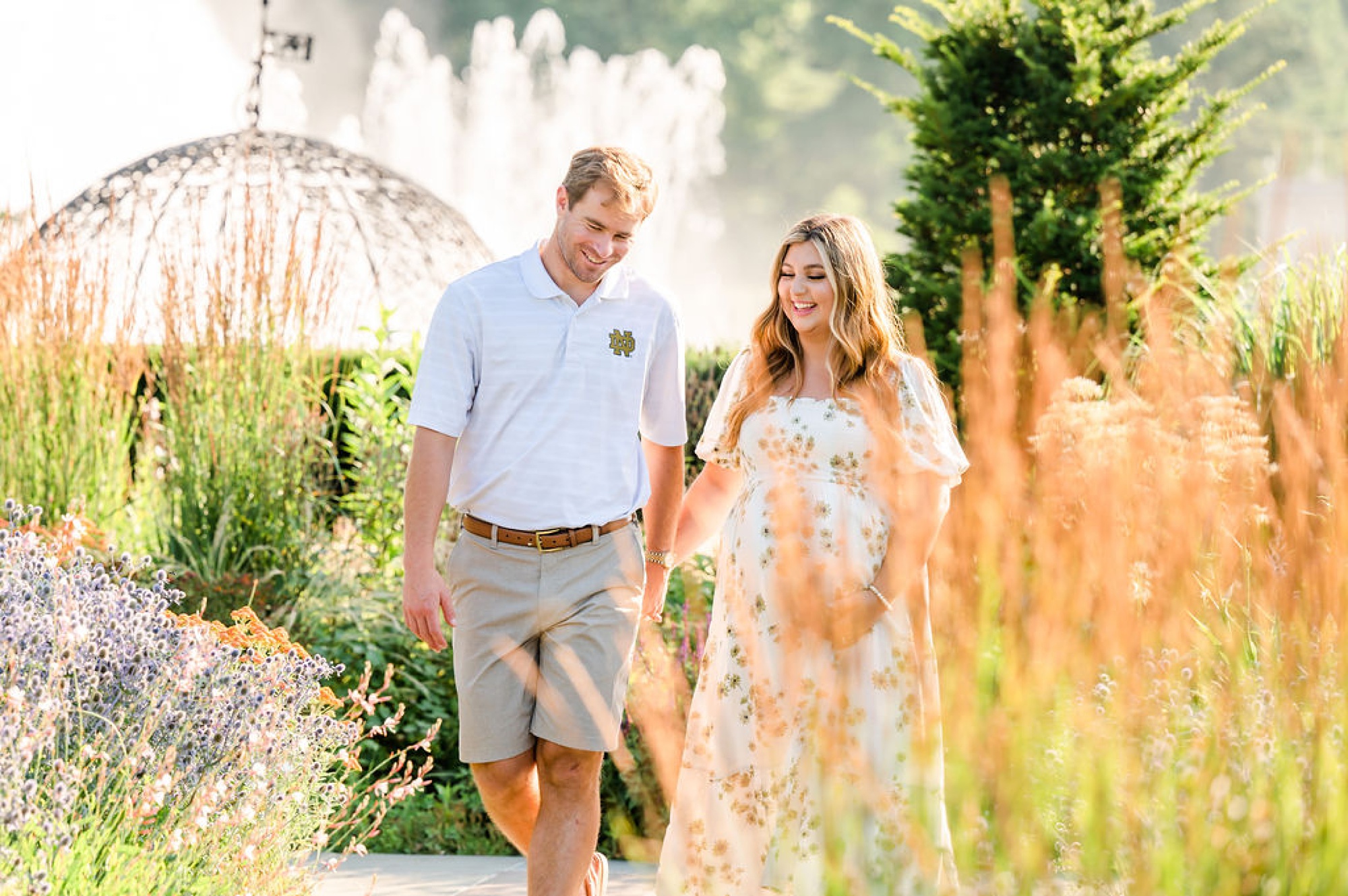 couple laughs walking thorough Longwood Gardens during maternity session 