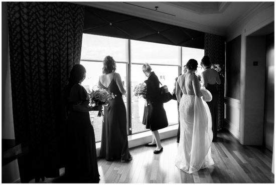 Bridesmaids looking at ceremony site though an upper window