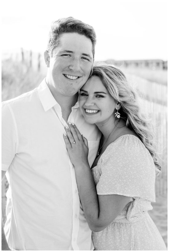 Bride has her hand on grooms chest while he looks at the camera. Beach Engagment Photos 
