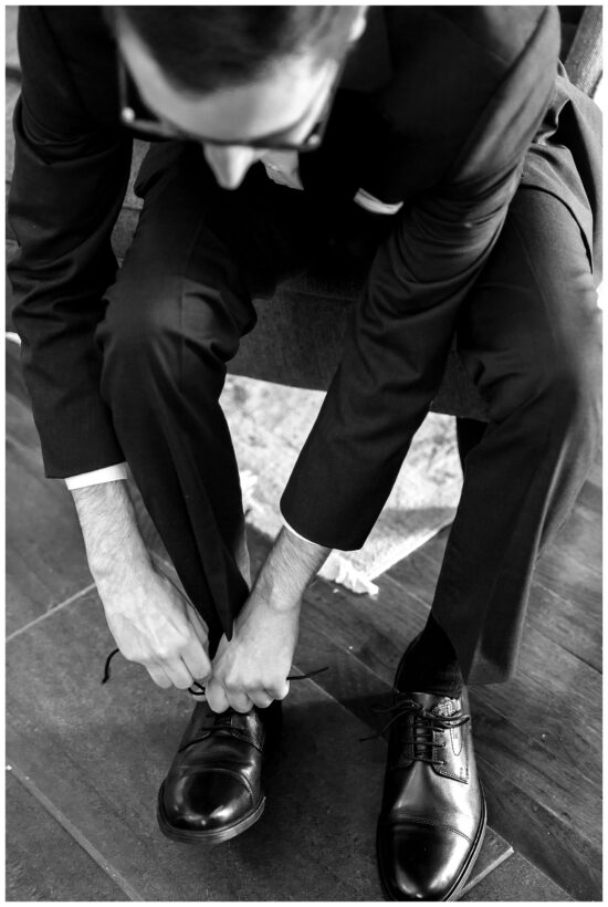 black and white photo of a groom fixing his tie